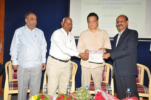 one man awarding certificate to another with 2 more men standing behind