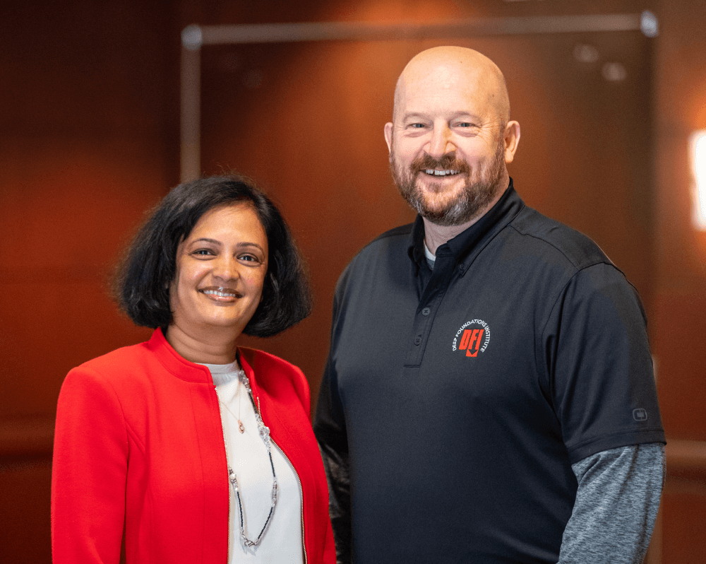 a woman and a man posing in front of wood paneling