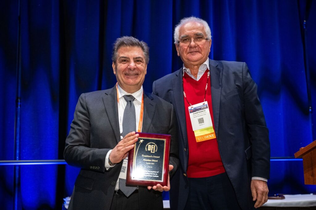 2 men posing for picture with an award plaque