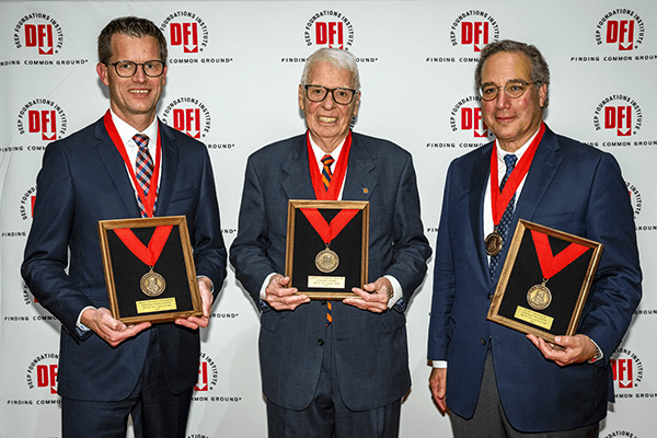 3 men holding plaques