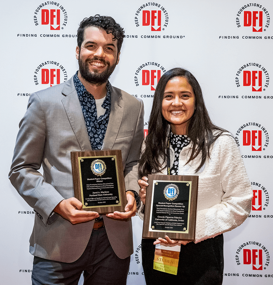 man and women smiling and holding plaques
