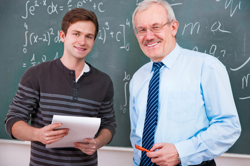 student and professor standing in front of chalk board