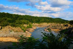 Wide landscape of a river cutting through rocky forested cliffs.